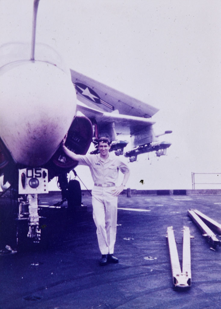 Michael Smith standing under a jet on the USS Kitty Hawk