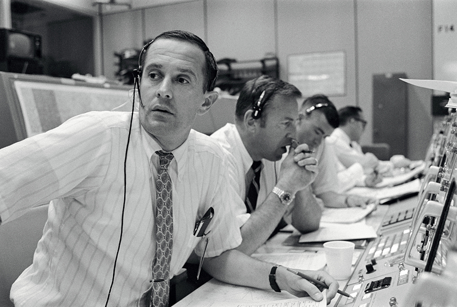 Charles Duke and three other men working in a NASA control room