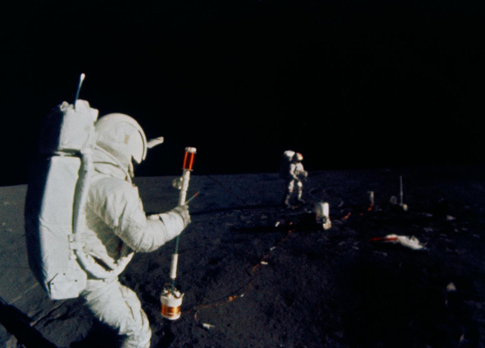 Two astronauts use the Thumper tool on the moon