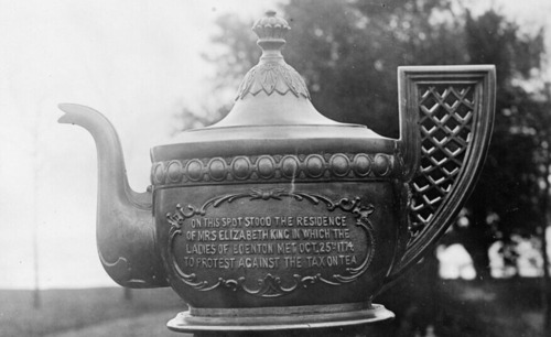 Photograph of a bronze teapot monument with an inscription on the front